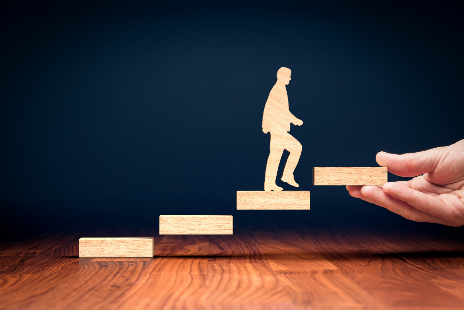 Wooden figure climbing steps assisted by a helping hand